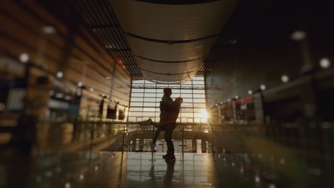 Silhouette of man and a woman meeting in airport terminal after arrival. People hugging. Concept of travel, tourism and transport. Sunset panoramic window at background. 6k downscale 10 bit.
