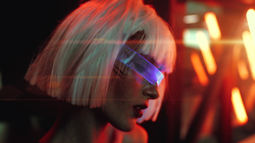 A woman in neon blue glasses is illuminated by a beautiful light with glare. High quality FullHD footage Royalty-Free Stock Footage #1062360313