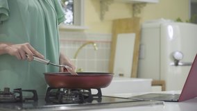 A young woman cooking while looking at the recipe site