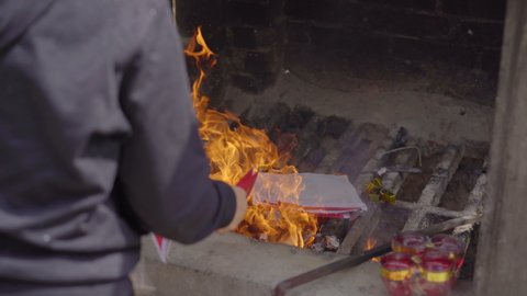 A person burns joss papers or offerings papers in a buddhist temple