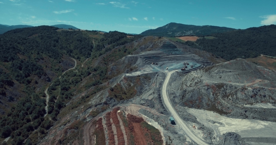 Panorama aerial view shot of the top opencast coal mining, quarrying extractive industry stripping work. Mining Trucks parked in the middle