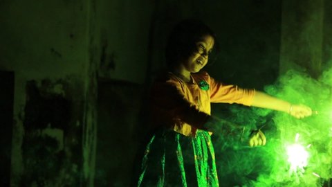 a cute indian girl child enjoying sparklers during diwali festival in dark background