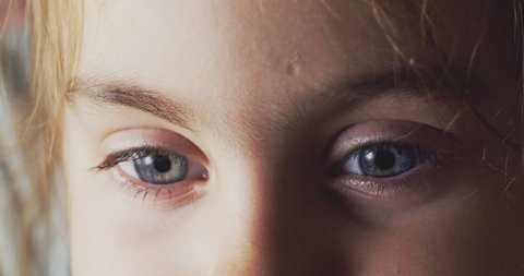 Beautiful blue eyes of a little girl. Close-up of a child's eyes, the closes her eyes and opens. Baby girl looks with blue eyes into the camera. Natural beauty of female.