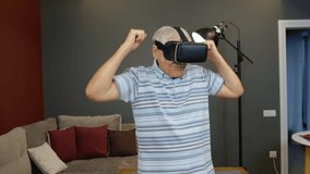 Happy senior man using virtual reality headset glasses. Elderly mature old grandfather rising his hand and trying to touch something, watching 3D video in 360 VR helmet. 6k downscale, slow motion