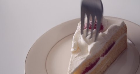 Man hand slowly sticks a fork into Japanese Strawberry Shortcake (Layer cake).