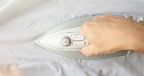 Man hand irons white clothes with a steam iron on an Ironing board. Top view. Сlose-up.