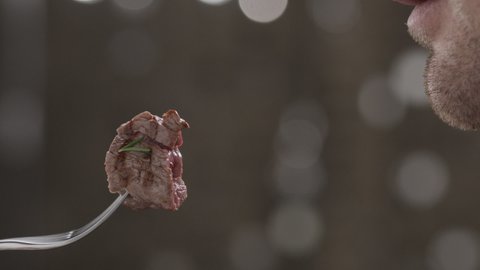 Close-up of unidentified european man eating a juicy slice of steak