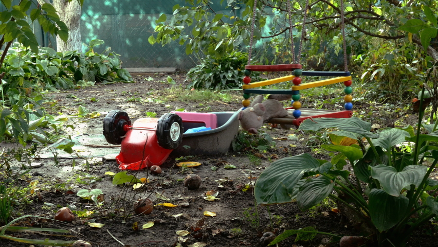 Stuffed toy swinging on swing in the backyard on an empty playground. Lack of life during coronavirus quarantine. Autumn view. Yellow leaves, wilting nature. Medium shot.