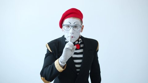 Portrait of guy mime looking around and shushing showing secret hand gesture and nodding head standing on white background. People and body language concept.