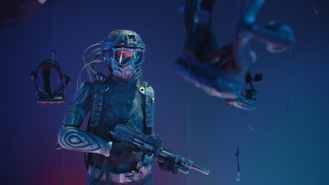 Female soldier of future with assault gun in her hands backlit with neon purple lights. Combat cyborg in futuristic protective suit standing in vr club. Cyberpunk warrior, cosplay, virtual reality