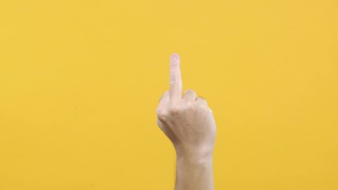 Man hand middle finger on yellow background.