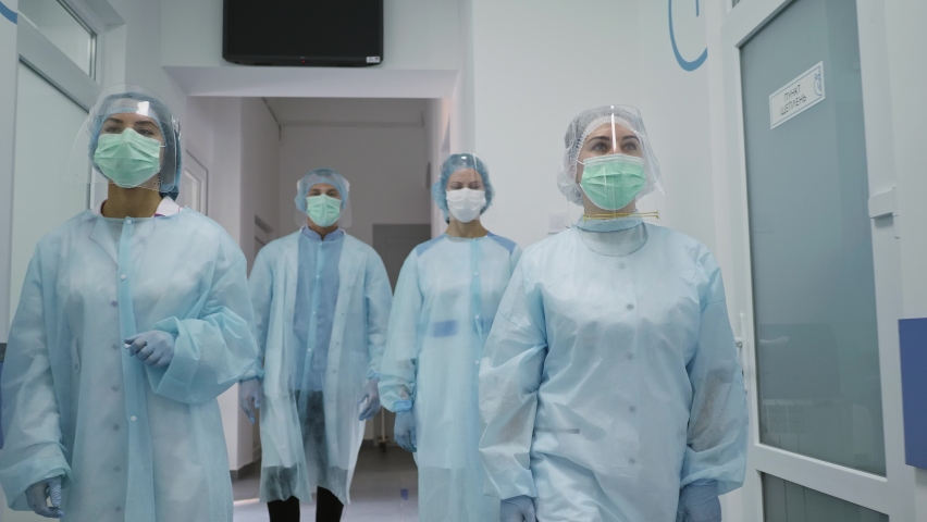 Team of Doctors in Protective Suits. Medical Workers Masked Walk Down the Corridor of a Modern Hospital. Fighting Covid-2019. | Shutterstock HD Video #1062395974