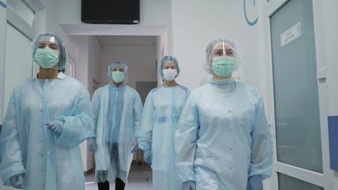 Team of Doctors in Protective Suits. Medical Workers Masked Walk Down the Corridor of a Modern Hospital. Fighting Covid-2019.