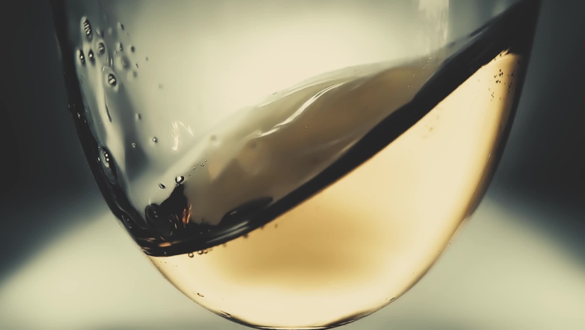 Creative macro slow motion video of white wine splashing in a glass from side to side like waves. Glass with splashing wine close-up. Old retro grunge vintage style. | Shutterstock HD Video #1062396439