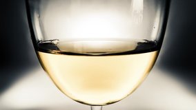 Creative macro slow motion video of white wine in a glass and a falling drops of wine. A glass with a slowly falling drops of wine close-up. Old retro grunge vintage style soft faded.