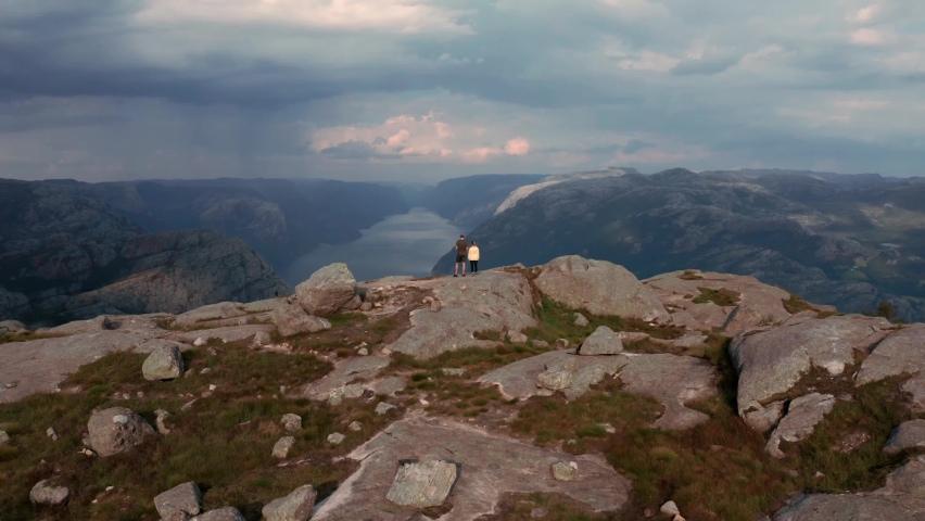 Preikestolen summer evening, overcast skies. Hiking couple looking into distance.
