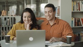 Smiling young couple making video call on laptop waving hand