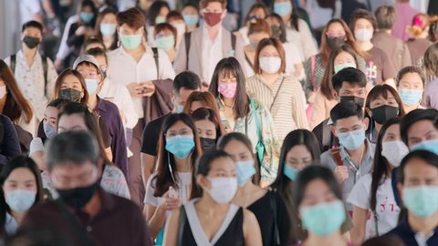 Bangkok, Thailand - Nov 6, 2020: Crowded Asian people wear face mask, walk in pedestrian walkway. Coronavirus Covid-19 pandemic, city life, commuter transportation or new normal lifestyle concept