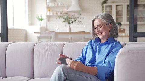 Old senior middle aged woman grandmother holding cell phone video conference calling in mobile app talking with social distance family or doctor in virtual online chat meeting on smartphone at home.