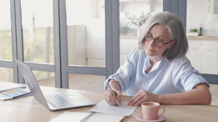 Senior older business woman distance teacher, online coach, lawyer, consultant talking working with documents, making video conference call virtual chat meeting on laptop working from home in office. Royalty-Free Stock Footage #1062406870