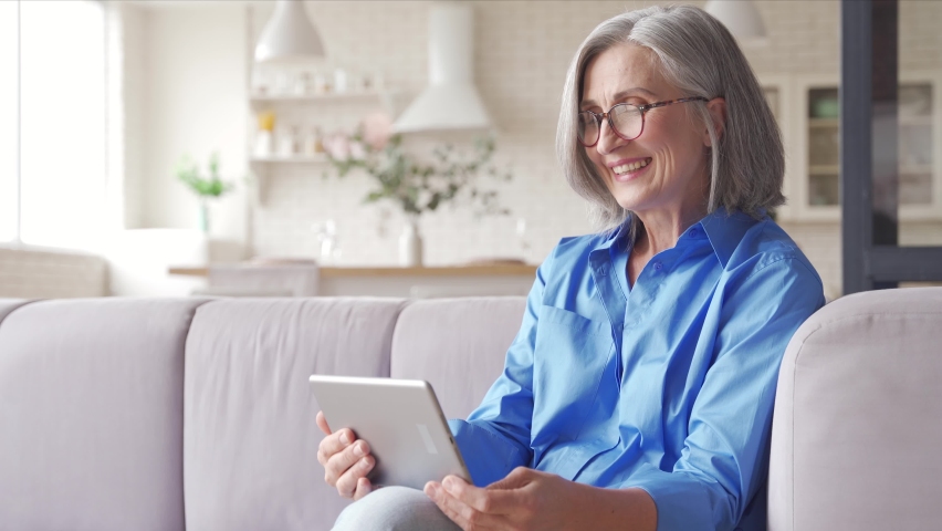 Happy old senior woman grandmother holding digital tablet video conference calling talking enjoying social distance party, virtual family online chat meeting with grandchildren on holiday at home. Royalty-Free Stock Footage #1062406873