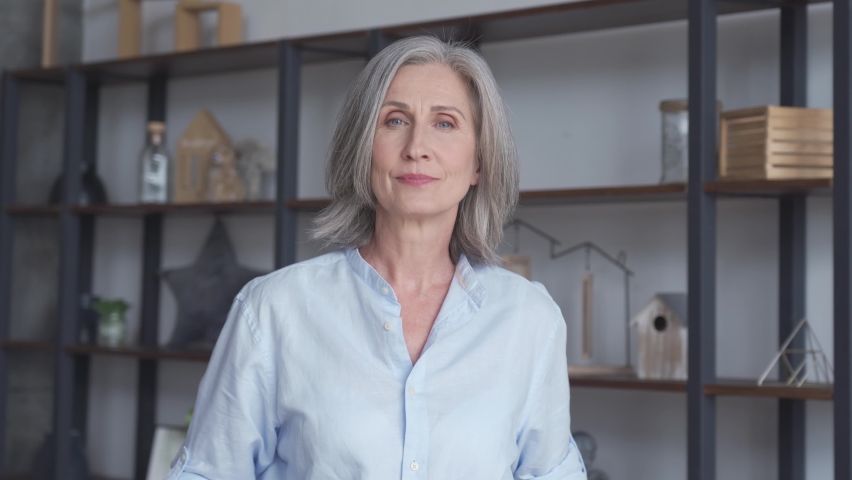 Smiling confident stylish mature mid aged woman standing at home office. Successful old senior businesswoman, 50s proud lady executive business leader manager looking at camera arms crossed, portrait. Royalty-Free Stock Footage #1062406897