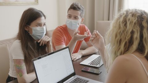 Modern international office. Workers and managers in medical masks working at laptop and discuss ideas. Buisness during coronavirus pandemic covid. People sitting at the table, brainstorm and create.