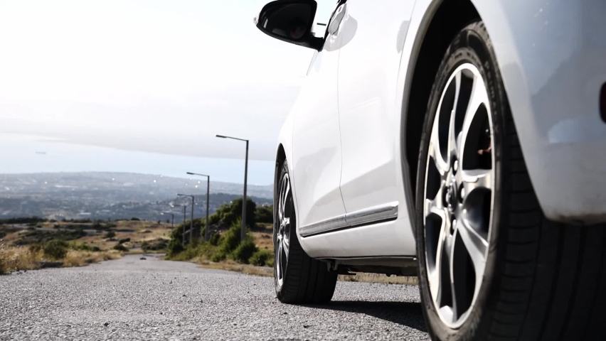 Low angle view of man getting out of car outdoors on empty road.