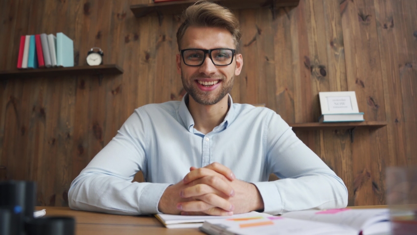 Young business man, remote teacher, professional distance coach talking to camera sitting at office desk conference video calling, giving webinar, online class, teaching or streaming, webcam view. | Shutterstock HD Video #1062408190