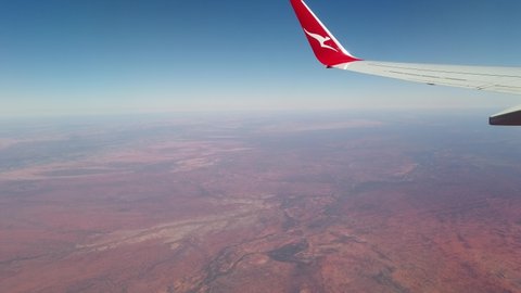 Alice Springs, Northern Territory, Australia - Aug 11, 2019: Flying airplane wing of Quanta airline on Alice Springs surrounding desert of Red Centre. Macdonnell ranges of Central Australia.