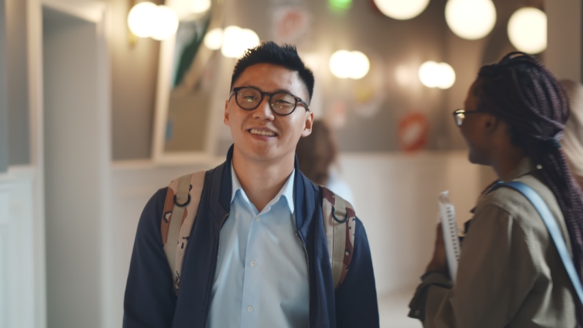 Portrait of smiling asian male student walking on corridor after classes. Positive young japanese college guy in glasses with backpack walking on university building hallway | Shutterstock HD Video #1062412630