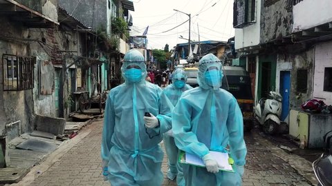 MUMBAI/INDIA- JUNE 17, 2020: Health workers wearing personal protective equipment arrive to conduct health check up at Ramabai nagar slum during the COVID-19 Coronavirus pandemic.