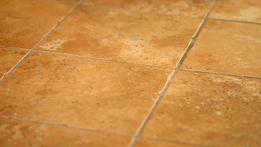 Cinematic prospective 4k shot of bathroom tile floor. Flooring tiles are made of ceramic in yellowish colors.