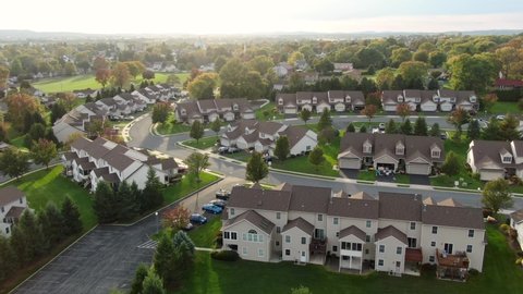 Townhouse condo apartment buildings during magic hour. Aerial drone shot above uniform tan brown houses in neighborhood community in USA.