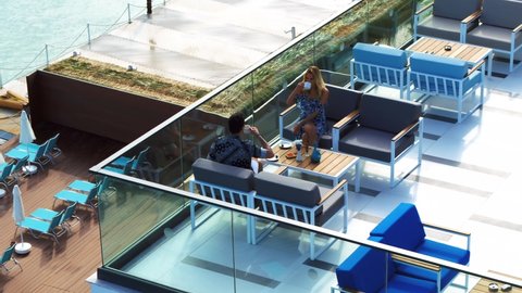 couple drinking coffee on the hotel's terrace with sea view, taken by drone.