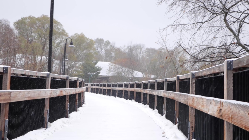 Snow-covered wooden bridge during fresh snowfall. Static. Chippewa River State Trail, Eau Claire Wisconsin across from Banbury.