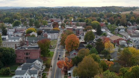 Rising aerial establishing shot of Anytown USA. Small town in America with colorful leaves. Church, school, homes in neighborhood community.