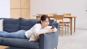 Asian woman using the smartphone on the sofa