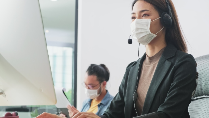 Asian team business people working in an office with anew normal social distancing lifestyle concept. Man and women wear protective face masks and keep distancing and working to prevent the COVID virus in the company. Royalty-Free Stock Footage #1062424810