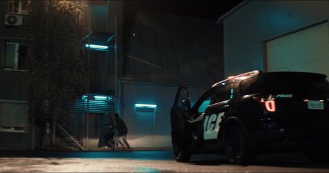 WIDE Criminals are running away as police car approaches with flashing lights at night. Shot on RED cinema camera with 2x Anamorphic lens
