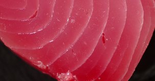 The flesh of fresh raw tuna rotates. On a black background. Texture of tuna.