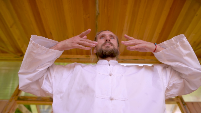 Close-up Bearded caucasian man wearing white clothes to practice concentration and breathing before practicing qigong tai chi