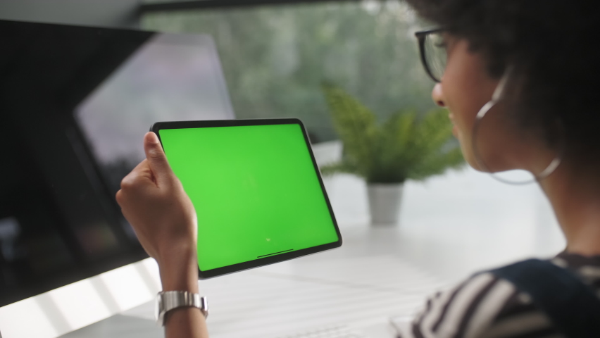 View From the Shoulder of Woman Using Hand Gestures Swipe Up on Green Mock-up Screen Digital Tablet Computer in Landscape Mode Sitting at The Desk in The Office. Royalty-Free Stock Footage #1062430807