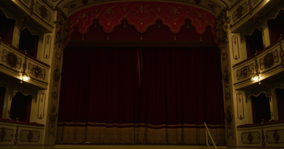 Wide shot of an Empty Elegant Classic Theatre with Big Stage and Red Velvet Curtains Opening. Well-lit Opera House with Beautiful Golden Decorations Ready to Recieve Audience for Play or Ballet Show  Royalty-Free Stock Footage #1062430972