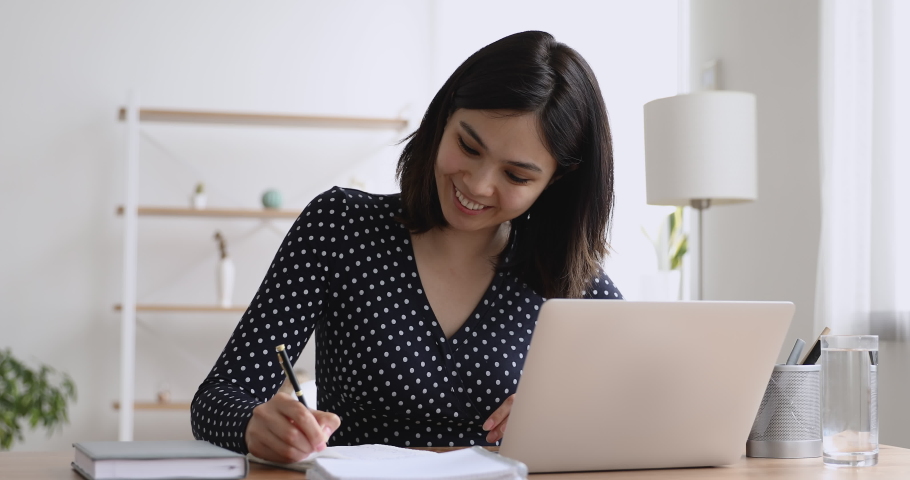 Happy millennial asian korean female student studying distantly using computer application, listening educational lecture, attending online class, checking homework, preparing for exams, writing notes Royalty-Free Stock Footage #1062431269