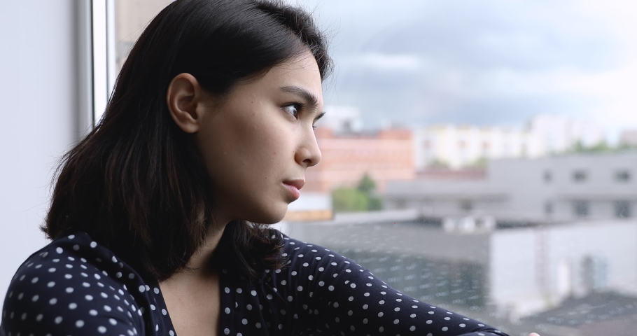 Head shot thoughtful korean asian woman looking out of window, feeling unsure about life decision, lost in thoughts millennial mixed race lady suffering from depressive melancholic mood alone at home. | Shutterstock HD Video #1062431281