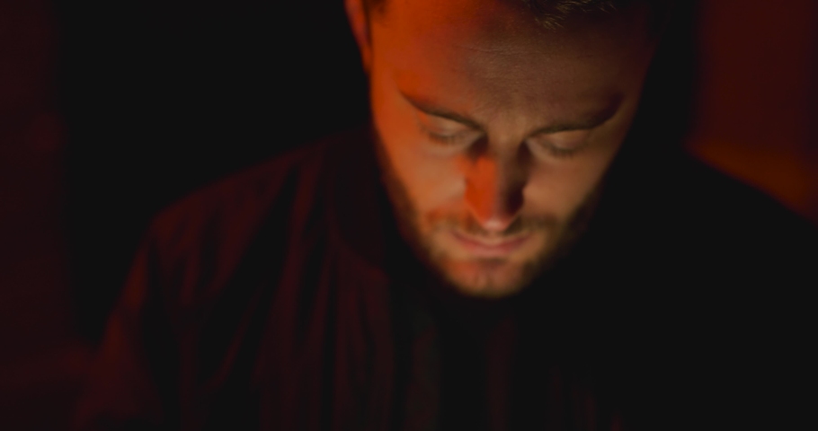 Young man using cell phone at night - lit by street light