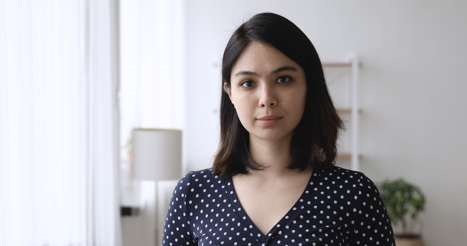 Head shot happy beautiful millennial korean asian woman looking at camera, standing in own apartment, smiling young mixed race renter client posing indoors, satisfied with real estate agency services. Royalty-Free Stock Footage #1062431350