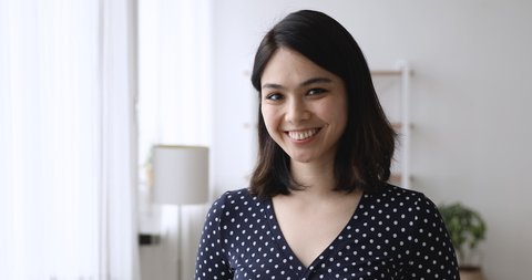 Head shot happy beautiful millennial korean asian woman looking at camera, standing in own apartment, smiling young mixed race renter client posing indoors, satisfied with real estate agency services.