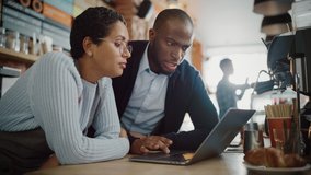 Two Diverse Entrepreneurs Have a Team Meeting in Their Stylish Coffee Shop. Barista and Cafe Owner Discuss Work Schedule and Menu on Laptop Computer. Multiethnic Female and Male Restaurant Employees. - Powered by Shutterstock - Get 15% off with code: PIKWIZARD15